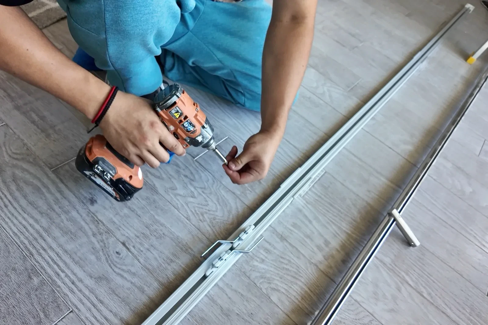 Installer fastening motorized curtain track hardware on the floor